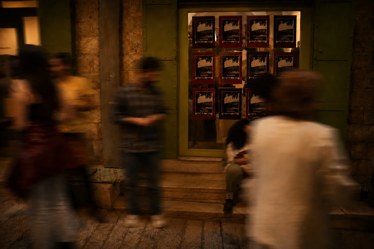 Passersby in front of the Saffuriya exhibition poster display at night