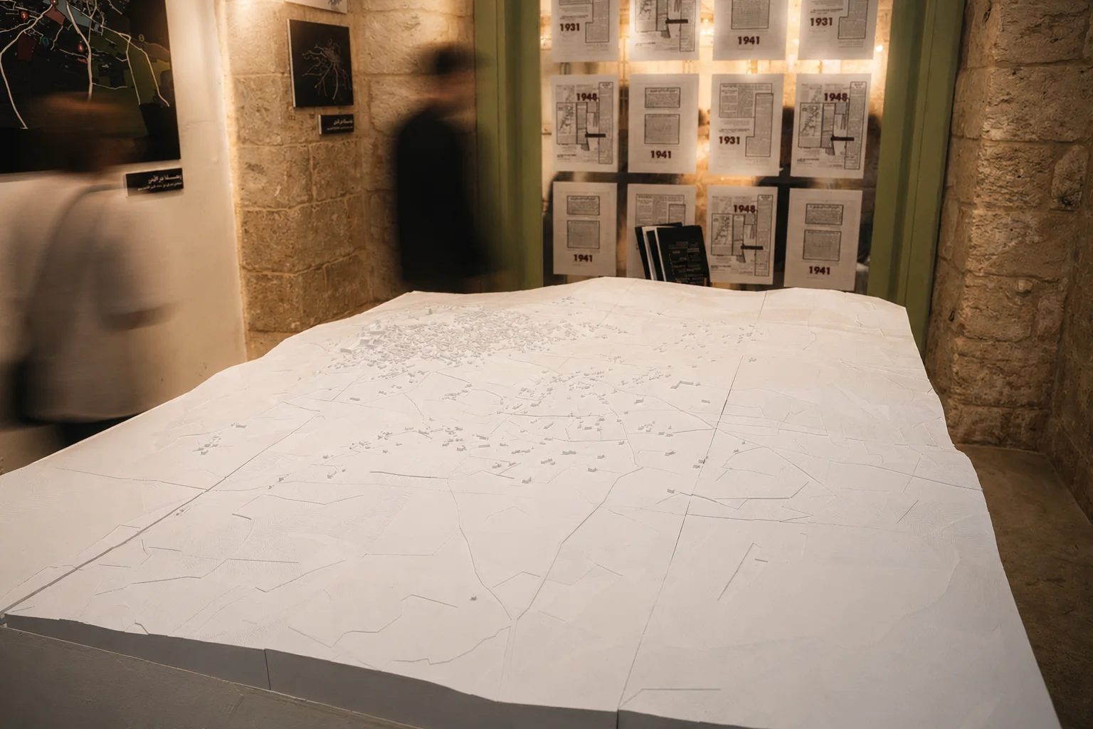 Large-scale architectural model of Saffuriya with archival documents on the wall