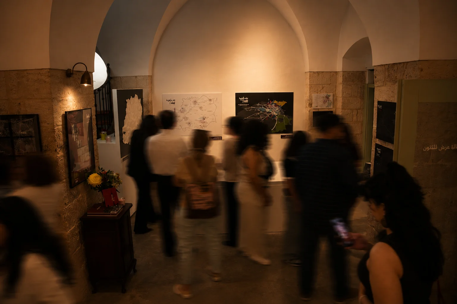 Visitors gathered in the arched exhibition hall viewing maps